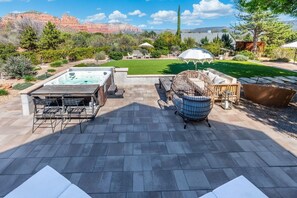 Une terrasse extérieure dotée d’un jacuzzi, d’un espace salon et offrant une vue sur un paysage naturel.