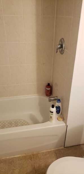 Kylpyhuoneessa on kylpyamme, wc ja sen vieressä on hyllyllä hygieniatarvikkeita.