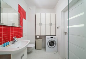 Un baño pequeño con lavamanos, inodoro y lavadora.