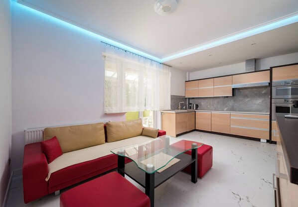 Una cocina moderna con electrodomésticos integrados y un sofá rojo en la sala.