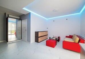 Un salon moderne avec une table basse en verre, un canapé rouge et beige, et un meuble en bois.