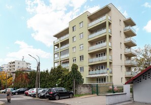 Un immeuble résidentiel à plusieurs étages, doté de balcons, d’une entrée sécurisée et de voitures garées.