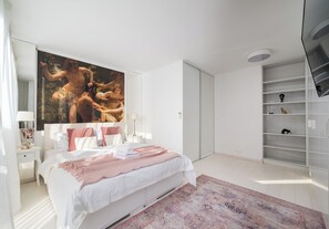 Un dormitorio moderno con una cama grande, una mesita de noche, un armario y una estantería empotrada.