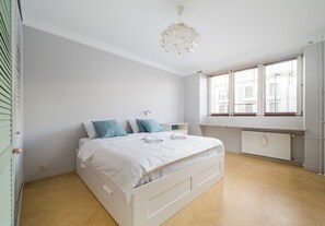 Un dormitorio con cama, radiador, ventana con persianas y lámpara colgante.