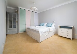 Une chambre à coucher comprenant un lit, une commode et une armoire aux portes de couleurs pastel.