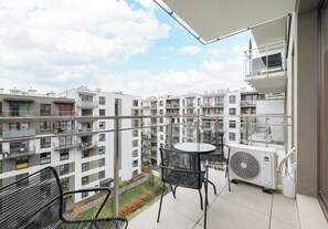 Un balcón con mesa y sillas, con vistas a una zona residencial con varios edificios de apartamentos.