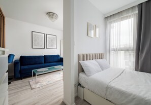 Un dormitorio moderno con una cama, un sofá azul y dos cuadros en la pared.