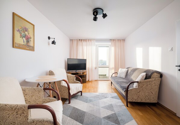 Una sala de estar con un sofá, un televisor, una mesita y una silla.