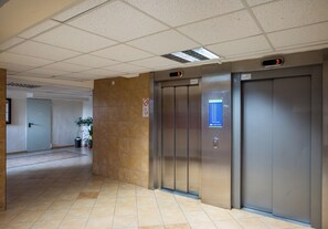 Un couloir intérieur avec deux portes d’ascenseur, l’une portant le numéro 5 et l’autre le numéro 3.