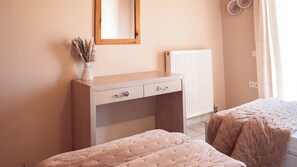 A bedroom with a wooden dresser, a mirror, a radiator, and two beds with pink bedding. - 3BR | Sea View | Entire Place | 100m from Beach | Olive Grove (Kipseli Drosia)