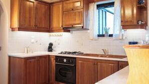 A kitchen with wooden cabinets, a gas stove, and a built-in oven. - 3BR | Sea View | Entire Place | 100m from Beach | Olive Grove (Kipseli Drosia)