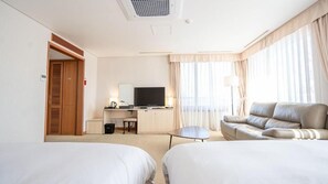 A hotel room with two beds, a sofa, a desk with a television, and a window with curtains. - Hotel Yeongildae (Pohang)