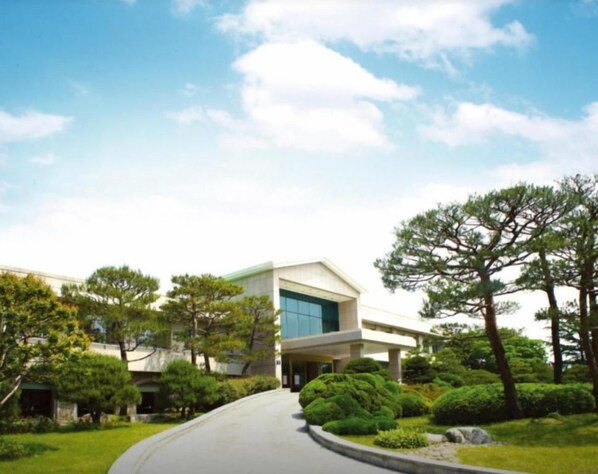 A modern building with a curved driveway, surrounded by well-maintained greenery and trees. - Hotel Yeongildae (Pohang)
