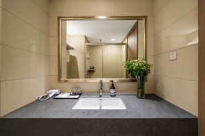 A bathroom with a large mirror, a sink, a shower, and a vase with flowers. - YI SELECT Hotel Hangzhou Qiandao Lake (Hangzhou)