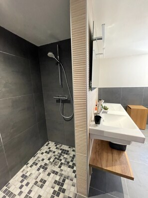 Un bagno moderno con doccia, lavabo e specchio.