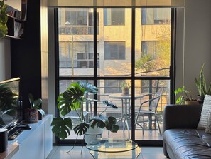 En moderne stue med et glasbord, en sofa og en balkon med udsigt over byen.
