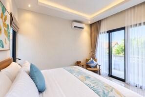 Ein Hotelzimmer mit einem großen Bett, einem kleinen Tisch, einem Stuhl, einer Klimaanlage und einem Balkon mit Vorhängen.