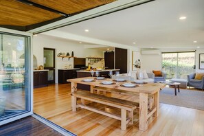 Una cucina moderna con mobili scuri, un tavolo da pranzo in legno apparecchiato per quattro persone e un'ampia finestra vista giardino.