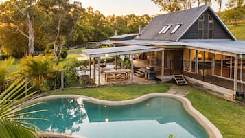 A house with a swimming pool, a covered patio, and a fenced backyard.