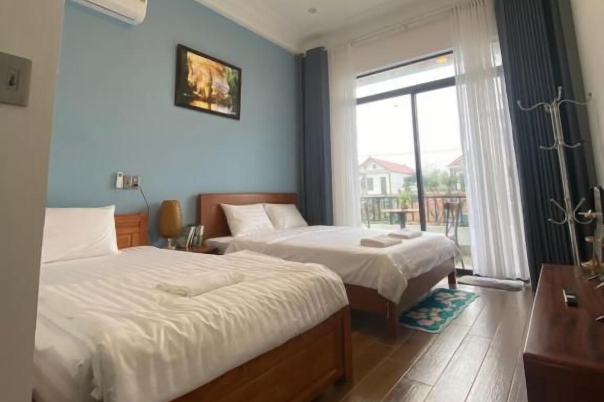 Habitación de hotel con dos camas, un aparador de madera, una ventana con cortinas y vistas al exterior.