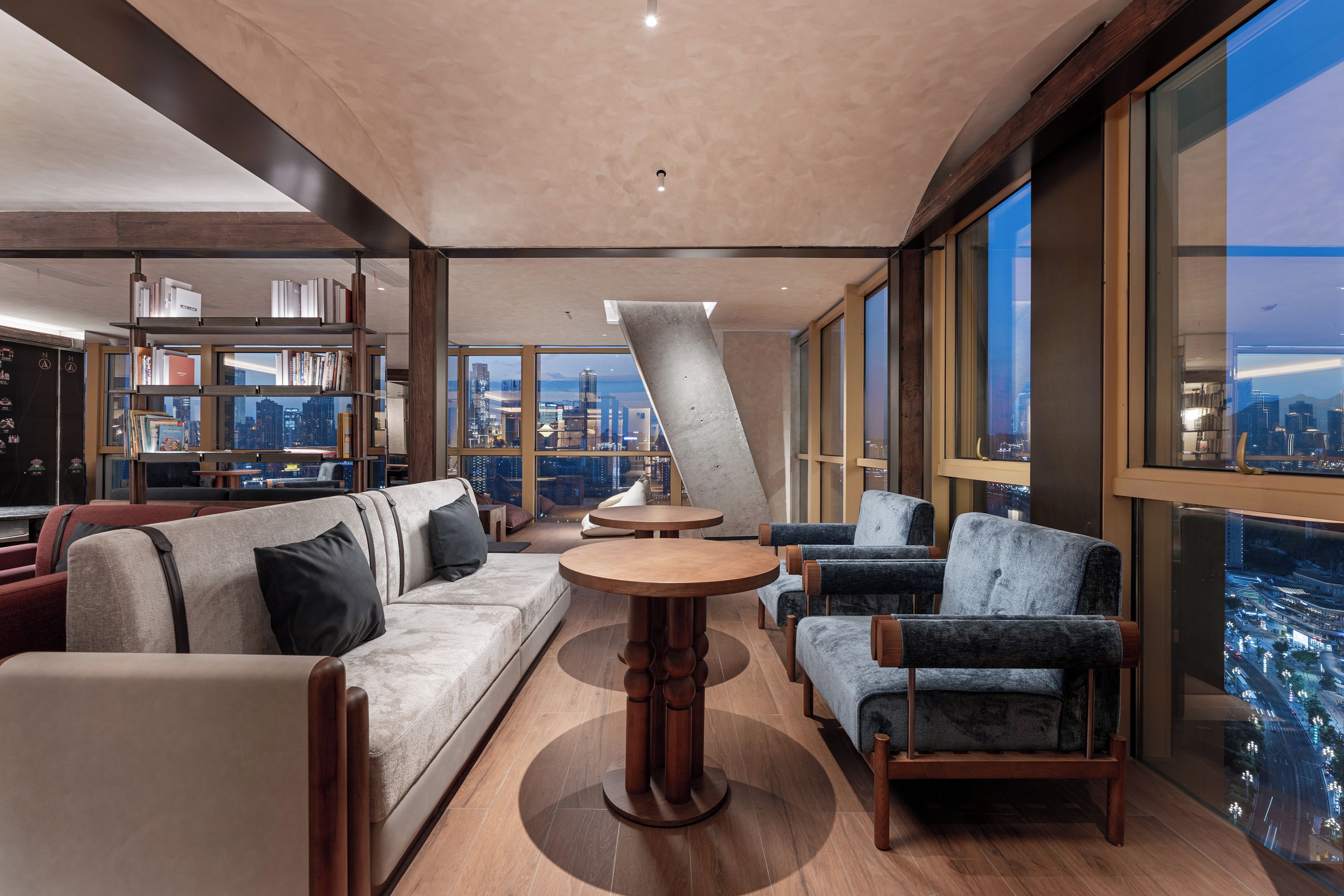 A modern living room with a sofa, armchairs, a coffee table, and a bookshelf.