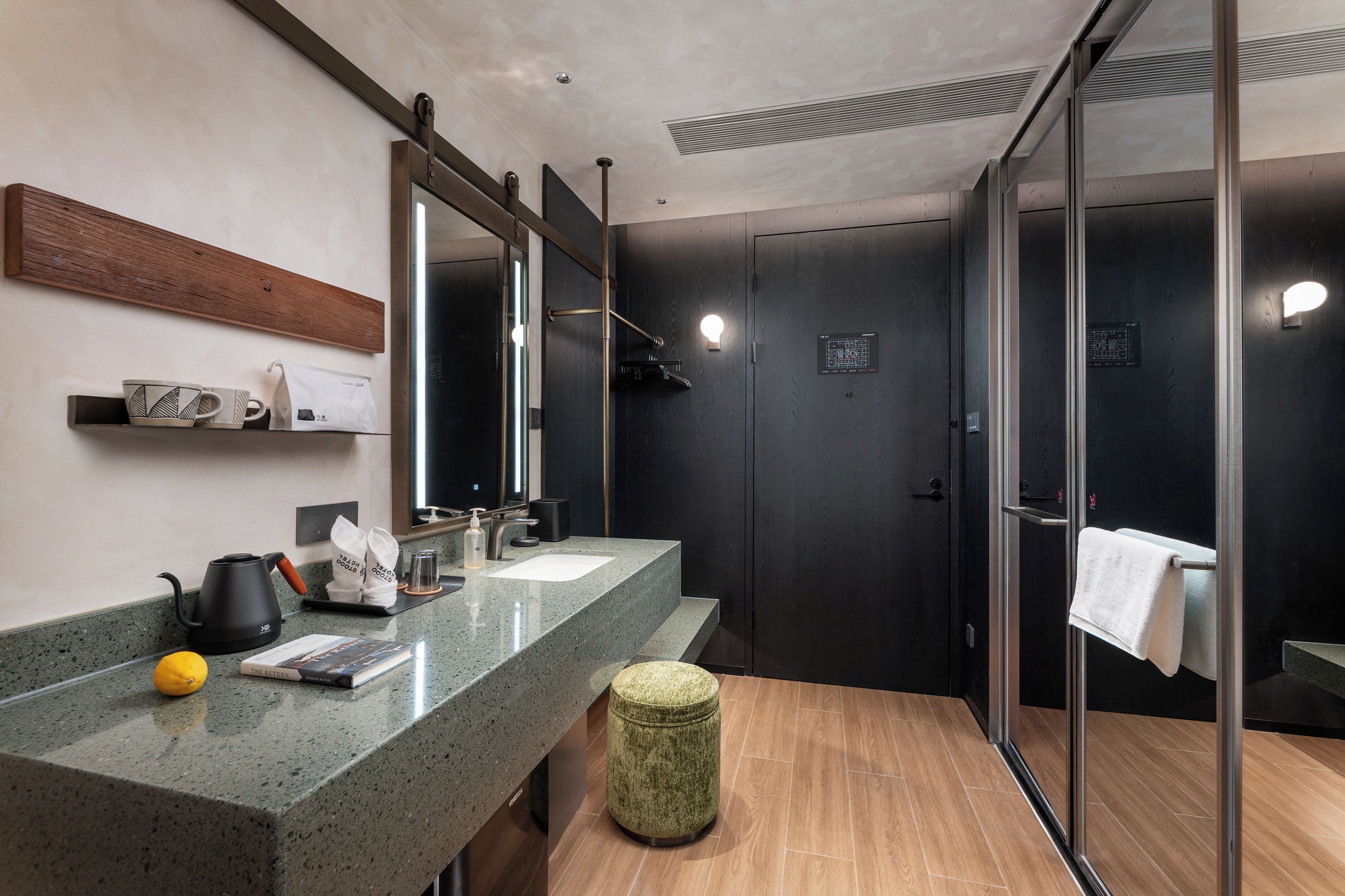 A modern bathroom with a granite countertop, a kettle, a book, and a towel rack.
