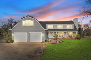 Ein zweistöckiges Haus mit Garage, überdachter Veranda und gepflegtem Rasen.