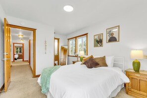 Ein Schlafzimmer mit einem großen Bett, Nachttischlampen, einem Holzschrank und Blick ins Bad.