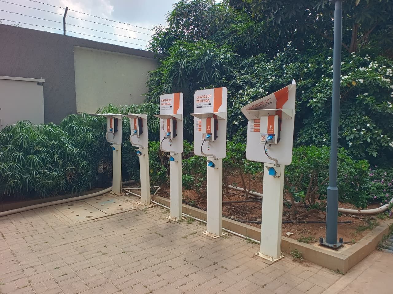 A row of electric vehicle charging stations with instructions to charge up with a Visa card.