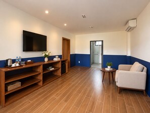 A hotel room with a flat-screen TV, wooden furniture, a sofa, and a small table. - Gio Bien Resort Phu Quoc  (An Giang)