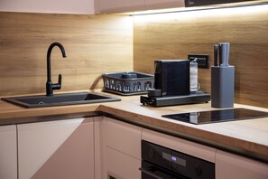 A modern kitchen with a black faucet, a coffee machine, and a built-in oven. - STOUNE BRIDGE APARTMENT 24 (Skopje)