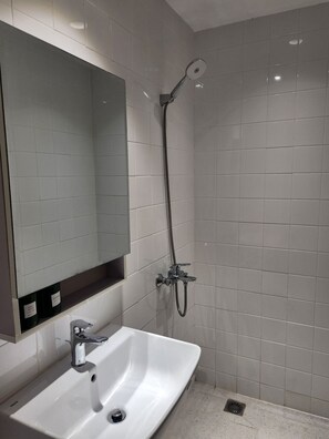 A bathroom with a white sink, a mirror, and a shower with a handheld showerhead. - D1 Heart · Rooftop•Kitchen•Lift · Mango @ Cozinema (Ben Thanh, District 1)