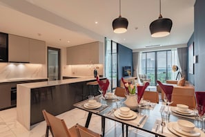 Una habitación de hotel moderna con comedor, cocina y sala de estar con vistas a la ciudad.