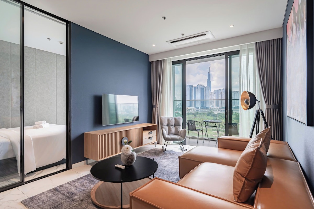 Una habitación de hotel moderna con cama, sofá, televisión, mesa de comedor y vistas a la ciudad.