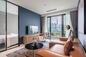 Una habitación de hotel moderna con cama, sofá, televisión, mesa de comedor y vistas a la ciudad.