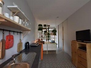 Eine kleine Küche mit Spüle, Arbeitsplatte und Fernseher auf einem Holzkabinett.