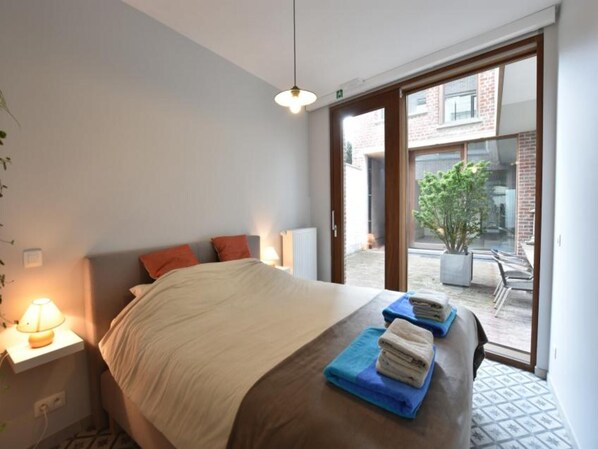 Ein Hotelzimmer mit Bett, Nachttischlampe, einem Fenster mit Ausblick und einem kleinen Tisch mit Handtüchern.