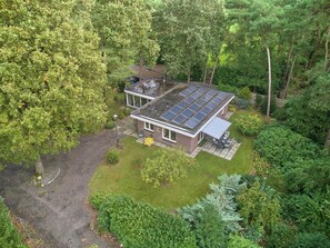 Une maison moderne dotée de panneaux solaires sur le toit, entourée d’une végétation luxuriante.