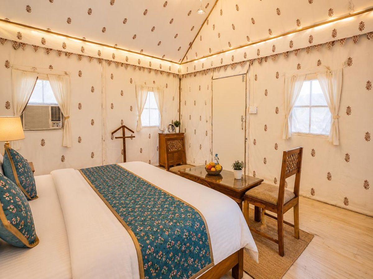 Une chambre d’hôtel avec un lit, une table, une chaise et un petit bureau.