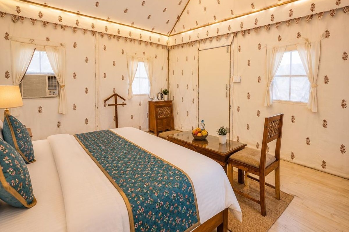 Une chambre d’hôtel avec un lit, une table, une chaise et un petit bureau.