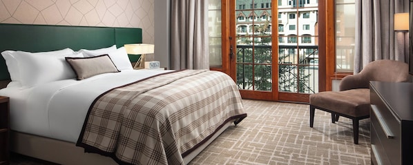 A hotel room with a bed, a chair, a nightstand, and a view of the outside. - New Year's Eve in Vail — Ritz-Carlton Club 3BR Residence (Vail)