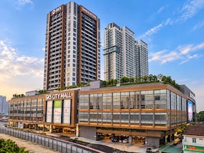 Ein modernes Bürogebäude mit mehreren Stockwerken, großen Glasfenstern und Beschilderung für 'SKS CITY MALL' und 'Village Grocer'.