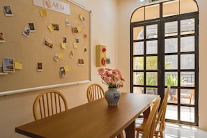 A room with a bulletin board, a vase with flowers, and a large window.