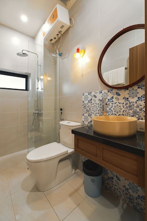 A modern bathroom with a toilet, sink, shower, and a mirror with a wooden frame.