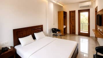 Habitación de hotel con una cama grande, un escritorio, una silla, un armario y un televisor.