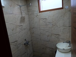 Ein Badezimmer mit Marmorwand, Dusche, Waschbecken und Fenster.