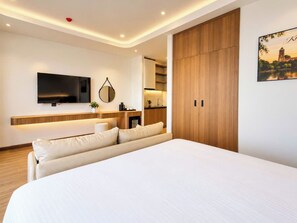 A modern hotel room with a large bed, a flat-screen TV mounted on the wall, a wooden wardrobe, and a small kitchenette area. - JOYA HOTEL PHU QUOC (Phu Quoc)
