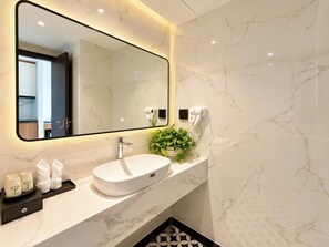 A modern bathroom with a marble sink, a large mirror, and a small plant on the vanity. - JOYA HOTEL PHU QUOC (Phu Quoc)