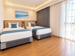 A hotel room with two beds, a large window with curtains, a painting on the wall, and a wooden floor. - JOYA HOTEL PHU QUOC (Phu Quoc)