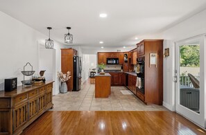 Cozinha moderna com armários de madeira, uma ilha central e vista para o exterior.
